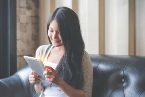 Beautiful woman reading a magazine online on tablet at coffee cafe Beautiful woman reading a magazine online on tablet at coffee cafe.