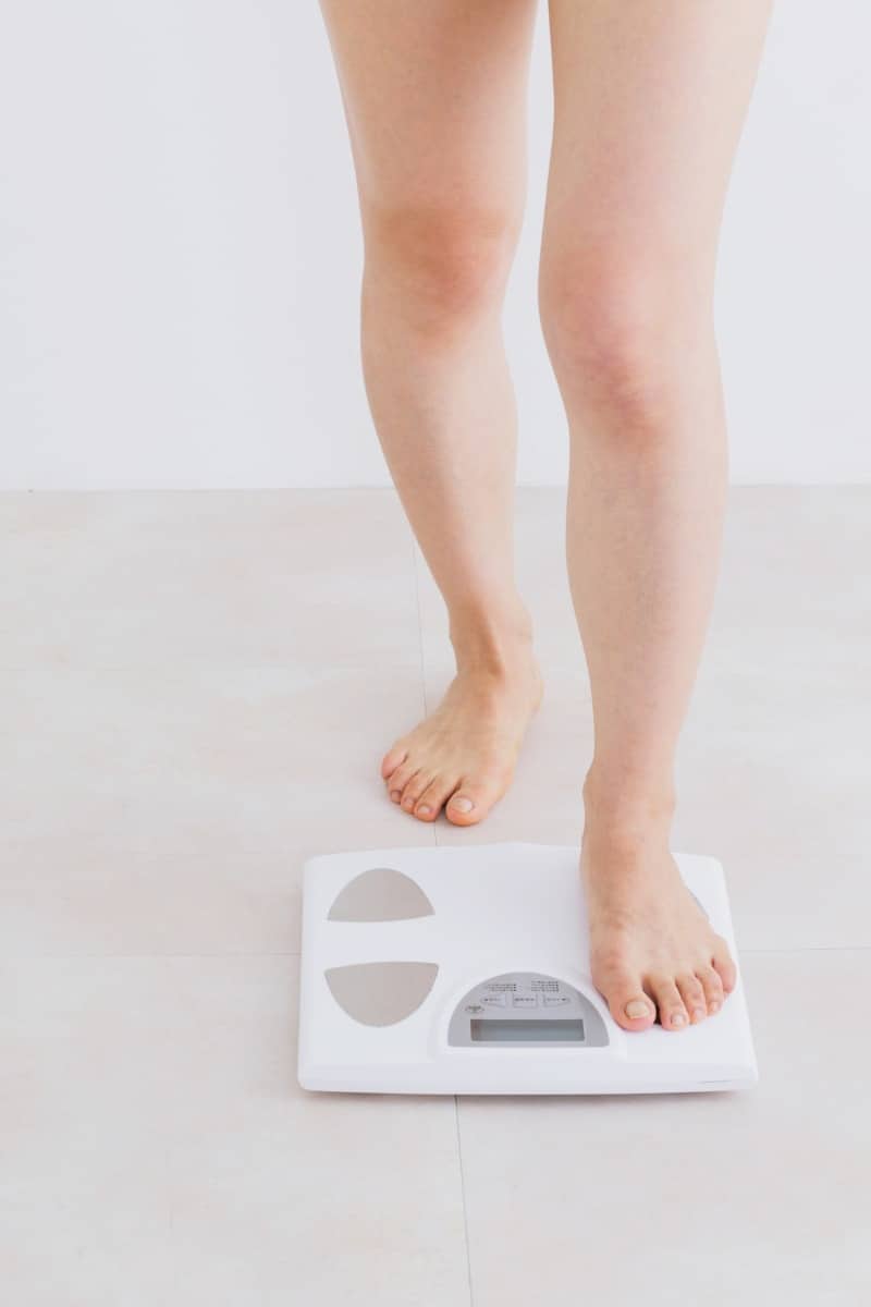 Weight-management-services Person stepping onto a digital scale to check body weight in a clean, neutral setting